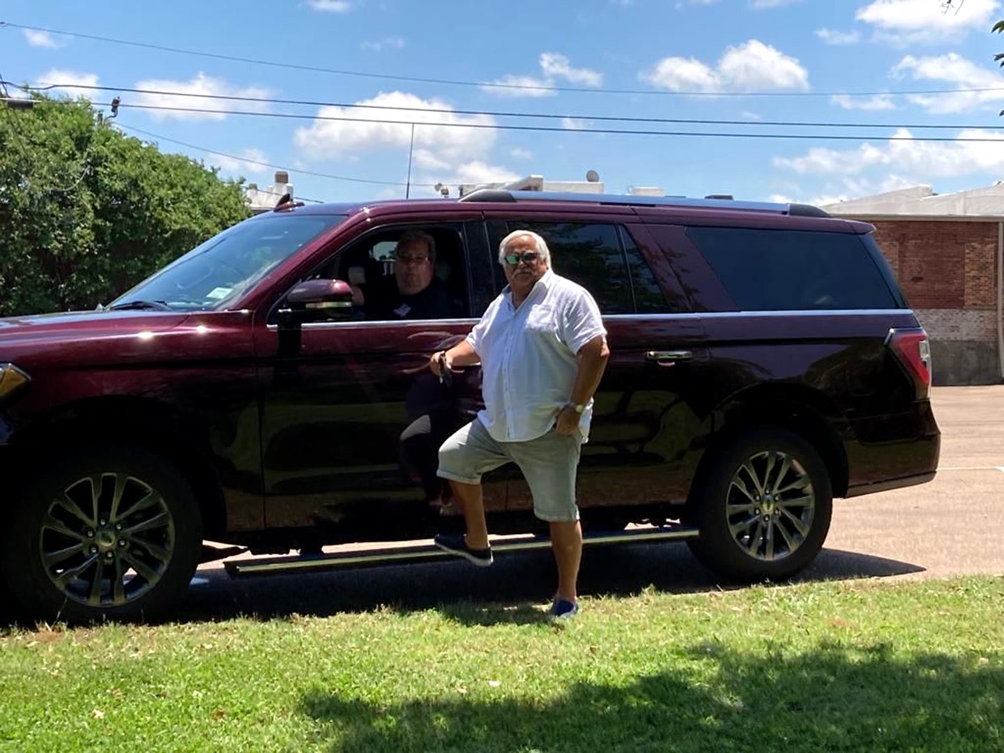 Thorsten Freimuth neben einem weinroten SUV mit weiterem Reisegast am Steuer